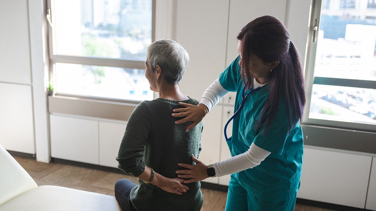 Older woman suffering from back pain during medical examination. 